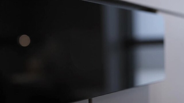 A finger taps a sleek black panel, initiating a responsive interface. A white light ring illuminates, indicating selection, before the screen fades back to black, demonstrating modern, minimalist app
