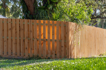 Wooden picket fence on green lawn surrounding property grounds for backyard protection and privacy