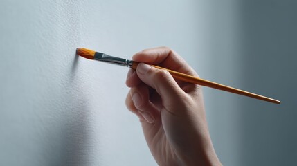 Hand Holding Paintbrush Applying Paint on Smooth Wall Surface in Artistic Process of Home Decoration and Creative Interior Design