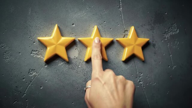 A hand touches a golden star among others on a textured grey background