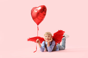 Obraz premium Cute little happy boy in cupid wings with heart-shaped balloon lying on pink background. Valentine's Day celebration