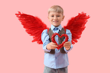 Obraz premium Cute little happy boy in cupid wings with heart-shaped decor on pink background. Valentine's Day celebration