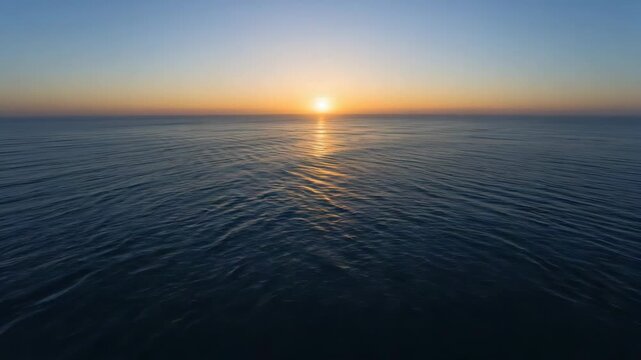 Calm ocean sunrise horizon with golden reflection calm sea and soft blue sky at dawn