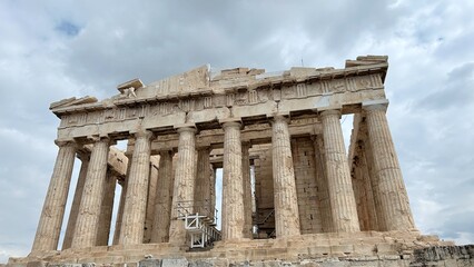 Fototapeta premium Iconic Parthenon temple on the Acropolis of Athens, showcasing ancient Greek architecture with tall Doric columns and marble structure. Dramatic cloudy sky enhances the historic monument.