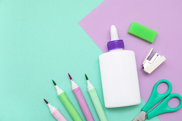 Bottle of glue, scissors and lilac sheet of paper on turquoise background. Top view