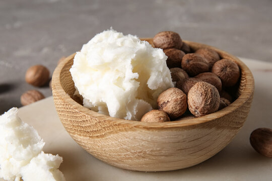 Bowl of shea butter and nuts on grey background