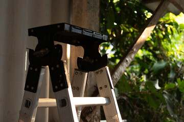 Close-up of a versatile aluminum folding ladder in a renovation area with sunlight highlighting the...