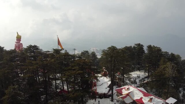Drone pulling back from Jakhu Temple to reveal giant Hanuman statue and Shimla city view.