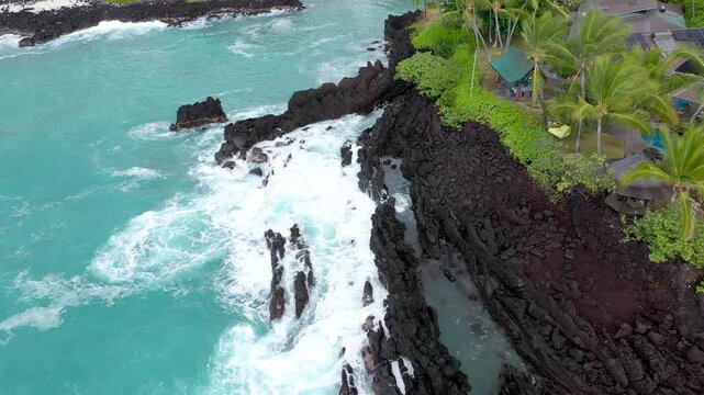 Top Down Drone Orbit of  Rugged Volcanic Beach and Turquoise Ocean next to luxurious house, Big Island Hawaii, 4K