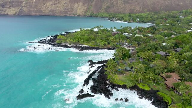 Aerial Drone Flight Over Luxury Oceanfront Estates and Lush Palm Trees, Powerful Waves Crashing on Volcanic Coast, Big Island Hawaii, 4K