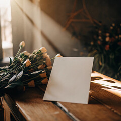 Cozy Romantic Valentine Background with Blank Paper, Fresh Spring Flowers, and Sun Rays