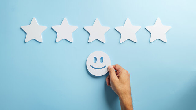 Feedback concept shows hand placing happy face beneath five white stars representing excellent customer satisfaction, positive service review experience for happy clients