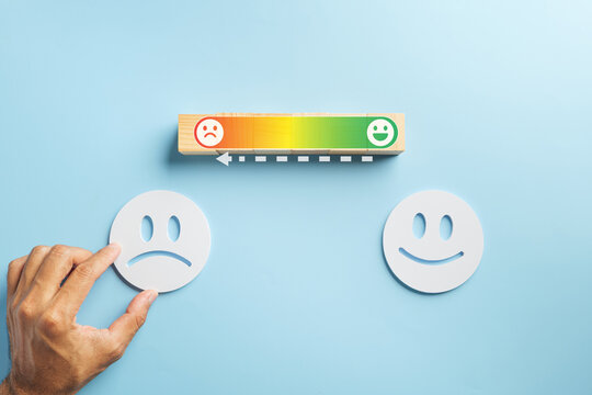 Hand repositions face, depicting customer experiance improve, transforming satisfaction servic concept from negative before to positive after, showing progress on a visual rating scale