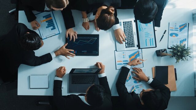 Top view of smart business people brainstorm marketing idea at meeting table while compare stock market investment data between laptop and tablet. Business team planning financial plan. Directorate.