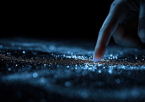 A finger touches a glowing, granular surface, suggesting interaction or data visualization