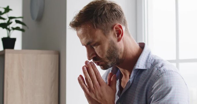 Man shows stress, anxiety, and deep worry. Hands pressed to face, he pauses in a room, focusing on breath, seeking relief from tension and uncertainty. Theme: mental health, anxiety, stress.
