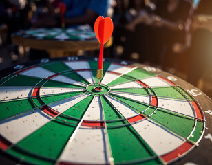 Fototapeta premium A red dart hits the bullseye of a green and white target, showcasing the instant of concentration and proficiency in a sociable contest. The atmosphere buzzes with exhilaration and expectation.