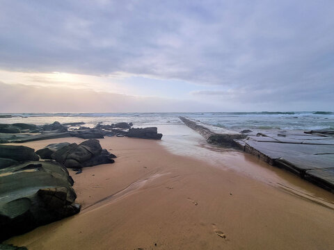 Rocks on Bar Beach Newcastle New South Wales Australia. Low tide early morning with a grey cloudy sky.
