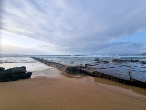 Rocks on Bar Beach Newcastle New South Wales Australia. Low tide early morning with a grey cloudy sky.
