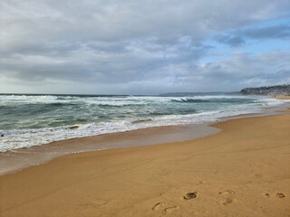 Fototapeta premium Waves on the sand at Bar Beach Newcastle New South Wales Australia early morning under a grey cloudy sky