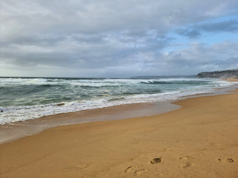 Waves on the sand at Bar Beach Newcastle New South Wales Australia early morning under a grey cloudy sky
