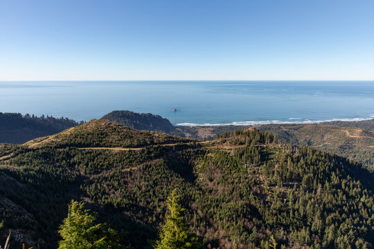 Scenic view from Angora Peak in the Oregon Coast Range overlooking coastal mountains near Cannon Beach and the Pacific Ocean with forested hills and a clear blue horizon.