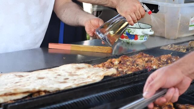 Cooking chicken and flatbread at outdoor grill stand