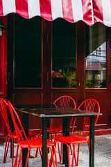 Red bistro chairs and striped awning at cozy outdoor cafe