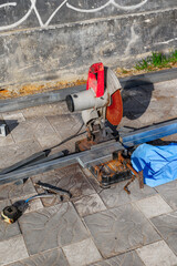 Industrial metal cutting saw on outdoor construction site with tools and equipment