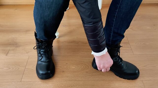 Seated on a wooden floor, I tie the laces of my favorite black combat boots - capturing a personal moment of style, routine, and readiness for the day ahead