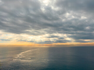 Obraz premium Dramatic cloudy sky over calm sea during golden sunset hour