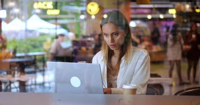 Middle-aged overworked multitasking successful business woman, entrepreneur, copywriter concentrated on planning her new project, using smartphone and laptop, telecommuting from a cafe interior