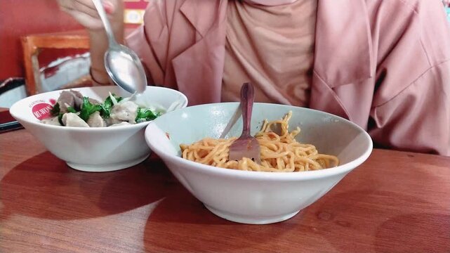 a woman eating Mie Bakso, or noodle soup with meatballs, one of the most popular cuisines in Indonesia on April 3, 2025 in Bandung, Indonesia