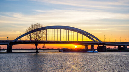 Obraz premium Lek bridge at sunset with a cargo ship passing underneath