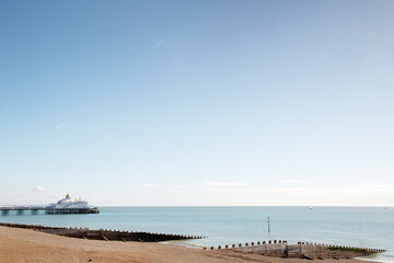 Fototapeta premium Quiet Coastal Scene With Pier, Beach and Calm Sea Under Clear Blue Sky