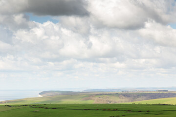 Coastal Hills Under a Cloudy Sky Over Green Fields and Distant Sea Cliffs