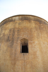 Old Circular Stone Tower With Small Arched Window and Weathered Exterior Texture