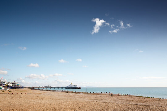 Sunny Beach With Pier, Calm Sea, And Clear Blue Sky Over the Horizon