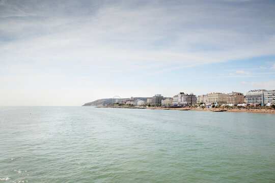 Sunny Coastal Town Beachfront With Ferris Wheel, Gentle Waves, And Oceanfront Buildings, Shoreline Panorama