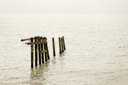 Old Wooden Pier Remnant Extends Into Calm Sea Under Muted Dusk Sky
