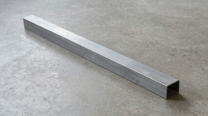 Fototapeta premium Long rectangular aluminum bar placed diagonally on industrial concrete floor with sharp shadows