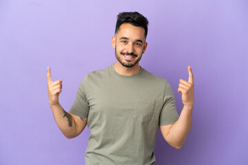 Fototapeta premium Young caucasian man isolated on purple background pointing up a great idea