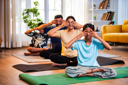 Indian parents and kids practicing bhramari bee breathing pranayama at home in morning