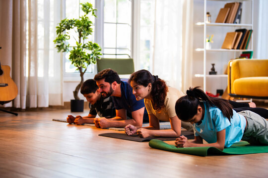 Indian young family performing plank exercise for core strength on floor at home