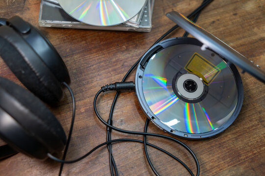 Listening to music on CDs.An optical disc with music in the CD player.Old school.Wired headphones on the table.