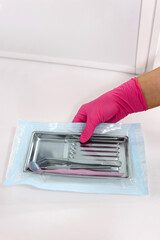 Sterile dental tray with instruments sealed in medical package on clean white background
