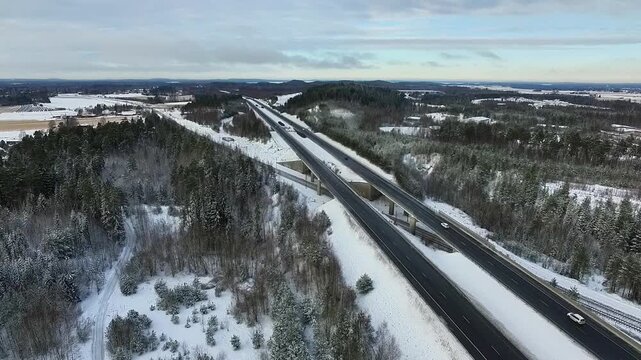 Aerial View of Snow-Covered Highway Surrounded by Lush Green Forest and Winter Landscape in Finland