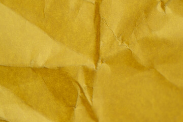 Naklejka premium Crinkled golden paper texture in warm sunlight creating soft shadows