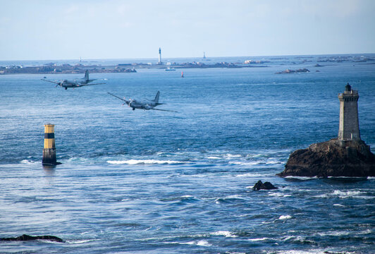 Avions militaires survolant un phare en pleine mer