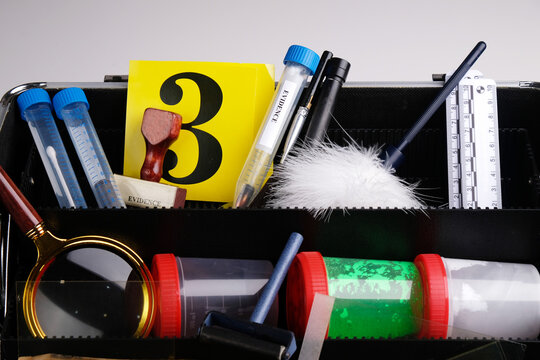 Forensic toolbox with crime scene examination tools: fingerprint brushes, powders, rulers, and  magnifying glass. Investigation and forensic science concepts.